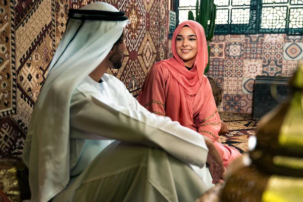 Emirati 'li genç bir çift geleneksel Arap kafesinde vakit geçiriyor. Kandura giyen kadın ve erkek Dubai 'den abaya sohbet ediyorlar..