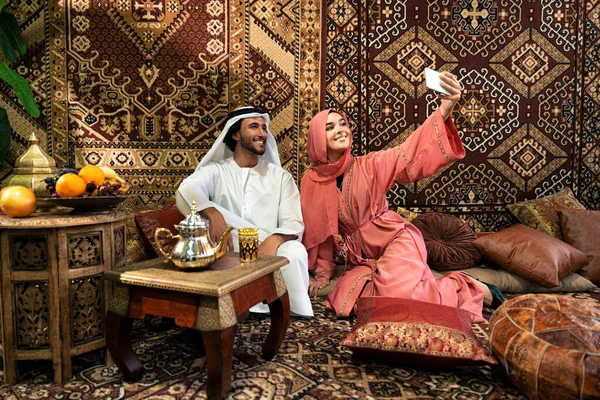 Emirati 'li genç bir çift geleneksel Arap kafesinde vakit geçiriyor. Kandura giyen kadın ve erkek Dubai 'den abaya sohbet ediyorlar..