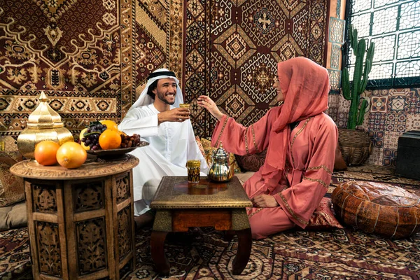 Emirati 'li genç bir çift geleneksel Arap kafesinde vakit geçiriyor. Kandura giyen kadın ve erkek Dubai 'den abaya sohbet ediyorlar..