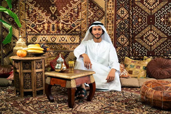 Emirati 'den kandura kıyafeti giyen bir adam Dubai' de geleneksel bir Arap evinde vakit geçiriyor.