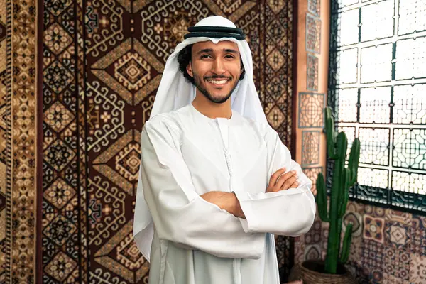 Emirati 'den kandura kıyafeti giyen bir adam Dubai' de geleneksel bir Arap evinde vakit geçiriyor.