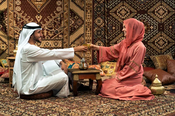 Emirati 'li genç bir çift geleneksel Arap kafesinde vakit geçiriyor. Kandura giyen kadın ve erkek Dubai 'den abaya sohbet ediyorlar..