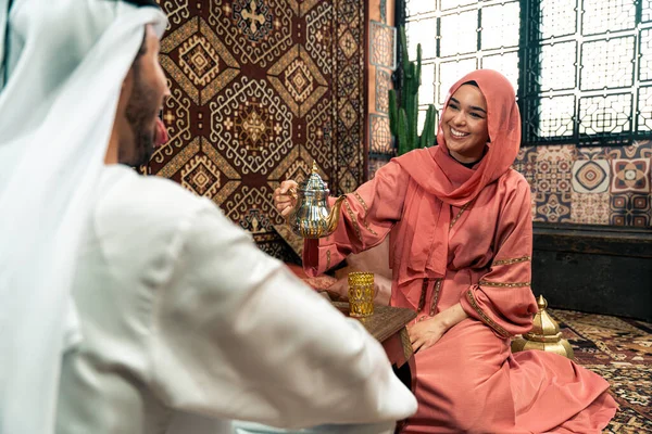 Emirati 'li genç bir çift geleneksel Arap kafesinde vakit geçiriyor. Kandura giyen kadın ve erkek Dubai 'den abaya sohbet ediyorlar..