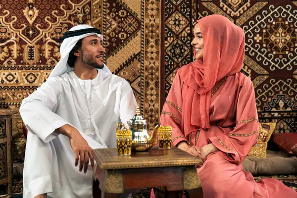 Emirati 'li genç bir çift geleneksel Arap kafesinde vakit geçiriyor. Kandura giyen kadın ve erkek Dubai 'den abaya sohbet ediyorlar..