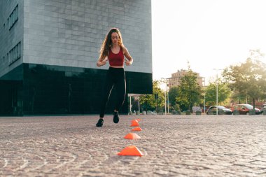 Güzel, sportif bir kız şehrin bir bölgesinde açık havada antrenman yapıyor.