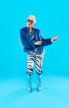 Mutlu ve komik yaşlı kadın rengarenk arka planda aşınabilir giysiler giyiyor modern havalı büyükanne portresi, yaşlı ve yaşlı insanlar hakkında kavramlar