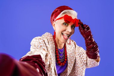 Mutlu ve komik yaşlı kadın rengarenk arka planda aşınabilir giysiler giyiyor modern havalı büyükanne portresi, yaşlı ve yaşlı insanlar hakkında kavramlar