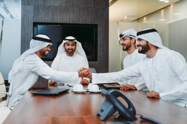 Bir grup Arap işadamı ofiste buluşuyor - Ortadoğulu iş adamları emirati kandora giyiyorlar, Dubai 'de bir toplantı odasında çalışıyorlar.