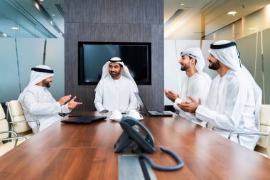 Bir grup Arap işadamı ofiste buluşuyor - Ortadoğulu iş adamları emirati kandora giyiyorlar, Dubai 'de bir toplantı odasında çalışıyorlar.
