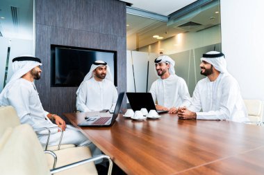 Bir grup Arap işadamı ofiste buluşuyor - Ortadoğulu iş adamları emirati kandora giyiyorlar, Dubai 'de bir toplantı odasında çalışıyorlar.