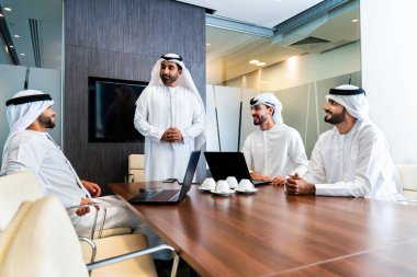 Bir grup Arap işadamı ofiste buluşuyor - Ortadoğulu iş adamları emirati kandora giyiyorlar, Dubai 'de bir toplantı odasında çalışıyorlar.