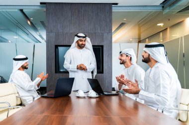 Bir grup Arap işadamı ofiste buluşuyor - Ortadoğulu iş adamları emirati kandora giyiyorlar, Dubai 'de bir toplantı odasında çalışıyorlar.