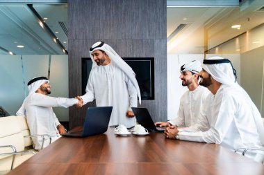 Bir grup Arap işadamı ofiste buluşuyor - Ortadoğulu iş adamları emirati kandora giyiyorlar, Dubai 'de bir toplantı odasında çalışıyorlar.