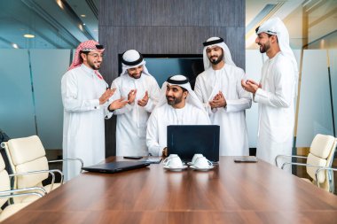 Bir grup Arap işadamı ofiste buluşuyor - Ortadoğulu iş adamları emirati kandora giyiyorlar, Dubai 'de bir toplantı odasında çalışıyorlar.