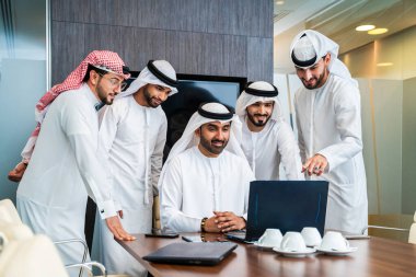 Bir grup Arap işadamı ofiste buluşuyor - Ortadoğulu iş adamları emirati kandora giyiyorlar, Dubai 'de bir toplantı odasında çalışıyorlar.