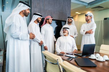 Bir grup Arap işadamı ofiste buluşuyor - Ortadoğulu iş adamları emirati kandora giyiyorlar, Dubai 'de bir toplantı odasında çalışıyorlar.