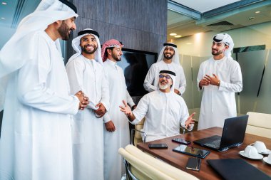Bir grup Arap işadamı ofiste buluşuyor - Ortadoğulu iş adamları emirati kandora giyiyorlar, Dubai 'de bir toplantı odasında çalışıyorlar.