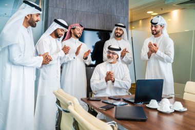 Bir grup Arap işadamı ofiste buluşuyor - Ortadoğulu iş adamları emirati kandora giyiyorlar, Dubai 'de bir toplantı odasında çalışıyorlar.