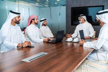 Bir grup Arap işadamı ofiste buluşuyor - Ortadoğulu iş adamları emirati kandora giyiyorlar, Dubai 'de bir toplantı odasında çalışıyorlar.