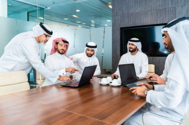 Bir grup Arap işadamı ofiste buluşuyor - Ortadoğulu iş adamları emirati kandora giyiyorlar, Dubai 'de bir toplantı odasında çalışıyorlar.