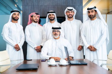 Bir grup Arap işadamı ofiste buluşuyor - Ortadoğulu iş adamları emirati kandora giyiyorlar, Dubai 'de bir toplantı odasında çalışıyorlar.