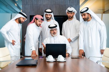 Bir grup Arap işadamı ofiste buluşuyor - Ortadoğulu iş adamları emirati kandora giyiyorlar, Dubai 'de bir toplantı odasında çalışıyorlar.