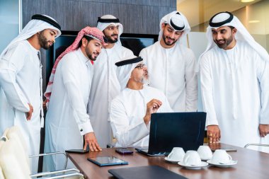Bir grup Arap işadamı ofiste buluşuyor - Ortadoğulu iş adamları emirati kandora giyiyorlar, Dubai 'de bir toplantı odasında çalışıyorlar.