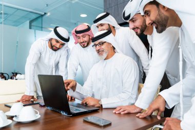 Bir grup Arap işadamı ofiste buluşuyor - Ortadoğulu iş adamları emirati kandora giyiyorlar, Dubai 'de bir toplantı odasında çalışıyorlar.