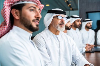 Bir grup Arap işadamı ofiste buluşuyor - Ortadoğulu iş adamları emirati kandora giyiyorlar, Dubai 'de bir toplantı odasında çalışıyorlar.