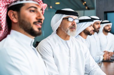 Bir grup Arap işadamı ofiste buluşuyor - Ortadoğulu iş adamları emirati kandora giyiyorlar, Dubai 'de bir toplantı odasında çalışıyorlar.