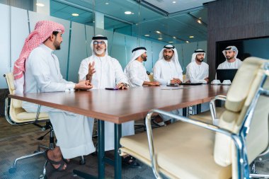 Bir grup Arap işadamı ofiste buluşuyor - Ortadoğulu iş adamları emirati kandora giyiyorlar, Dubai 'de bir toplantı odasında çalışıyorlar.