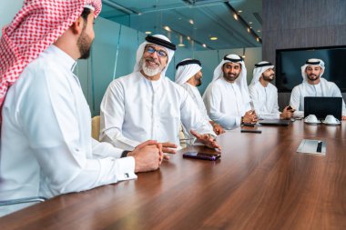 Bir grup Arap işadamı ofiste buluşuyor - Ortadoğulu iş adamları emirati kandora giyiyorlar, Dubai 'de bir toplantı odasında çalışıyorlar.
