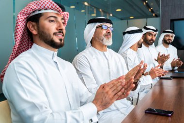 Bir grup Arap işadamı ofiste buluşuyor - Ortadoğulu iş adamları emirati kandora giyiyorlar, Dubai 'de bir toplantı odasında çalışıyorlar.