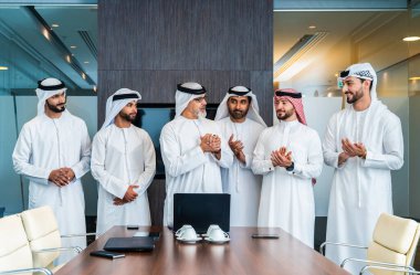 Bir grup Arap işadamı ofiste buluşuyor - Ortadoğulu iş adamları emirati kandora giyiyorlar, Dubai 'de bir toplantı odasında çalışıyorlar.