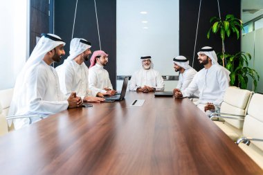 Bir grup Arap işadamı ofiste buluşuyor - Ortadoğulu iş adamları emirati kandora giyiyorlar, Dubai 'de bir toplantı odasında çalışıyorlar.