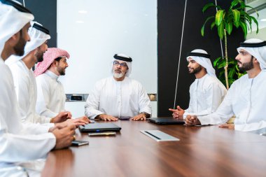 Bir grup Arap işadamı ofiste buluşuyor - Ortadoğulu iş adamları emirati kandora giyiyorlar, Dubai 'de bir toplantı odasında çalışıyorlar.