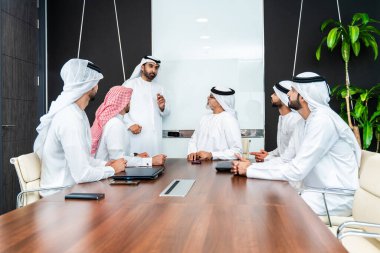 Bir grup Arap işadamı ofiste buluşuyor - Ortadoğulu iş adamları emirati kandora giyiyorlar, Dubai 'de bir toplantı odasında çalışıyorlar.