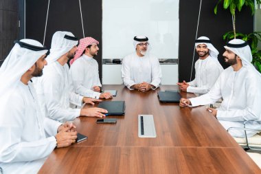 Bir grup Arap işadamı ofiste buluşuyor - Ortadoğulu iş adamları emirati kandora giyiyorlar, Dubai 'de bir toplantı odasında çalışıyorlar.