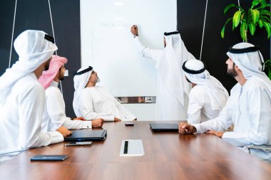 Bir grup Arap işadamı ofiste buluşuyor - Ortadoğulu iş adamları emirati kandora giyiyorlar, Dubai 'de bir toplantı odasında çalışıyorlar.