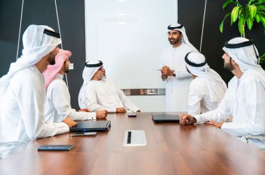 Bir grup Arap işadamı ofiste buluşuyor - Ortadoğulu iş adamları emirati kandora giyiyorlar, Dubai 'de bir toplantı odasında çalışıyorlar.