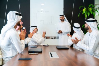 Bir grup Arap işadamı ofiste buluşuyor - Ortadoğulu iş adamları emirati kandora giyiyorlar, Dubai 'de bir toplantı odasında çalışıyorlar.
