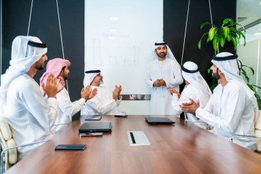 Bir grup Arap işadamı ofiste buluşuyor - Ortadoğulu iş adamları emirati kandora giyiyorlar, Dubai 'de bir toplantı odasında çalışıyorlar.
