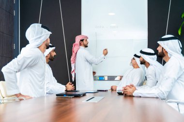 Bir grup Arap işadamı ofiste buluşuyor - Ortadoğulu iş adamları emirati kandora giyiyorlar, Dubai 'de bir toplantı odasında çalışıyorlar.