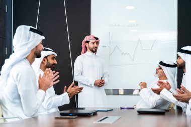 Bir grup Arap işadamı ofiste buluşuyor - Ortadoğulu iş adamları emirati kandora giyiyorlar, Dubai 'de bir toplantı odasında çalışıyorlar.