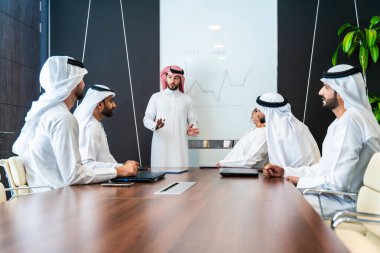Bir grup Arap işadamı ofiste buluşuyor - Ortadoğulu iş adamları emirati kandora giyiyorlar, Dubai 'de bir toplantı odasında çalışıyorlar.