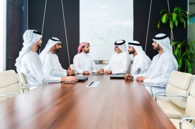 Bir grup Arap işadamı ofiste buluşuyor - Ortadoğulu iş adamları emirati kandora giyiyorlar, Dubai 'de bir toplantı odasında çalışıyorlar.