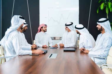 Bir grup Arap işadamı ofiste buluşuyor - Ortadoğulu iş adamları emirati kandora giyiyorlar, Dubai 'de bir toplantı odasında çalışıyorlar.