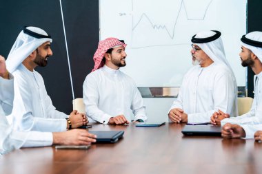 Bir grup Arap işadamı ofiste buluşuyor - Ortadoğulu iş adamları emirati kandora giyiyorlar, Dubai 'de bir toplantı odasında çalışıyorlar.