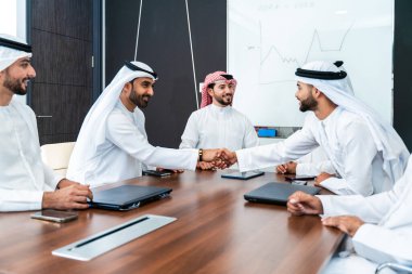 Bir grup Arap işadamı ofiste buluşuyor - Ortadoğulu iş adamları emirati kandora giyiyorlar, Dubai 'de bir toplantı odasında çalışıyorlar.