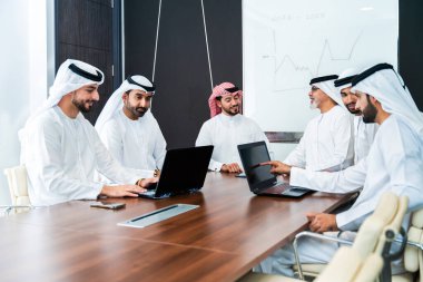 Bir grup Arap işadamı ofiste buluşuyor - Ortadoğulu iş adamları emirati kandora giyiyorlar, Dubai 'de bir toplantı odasında çalışıyorlar.